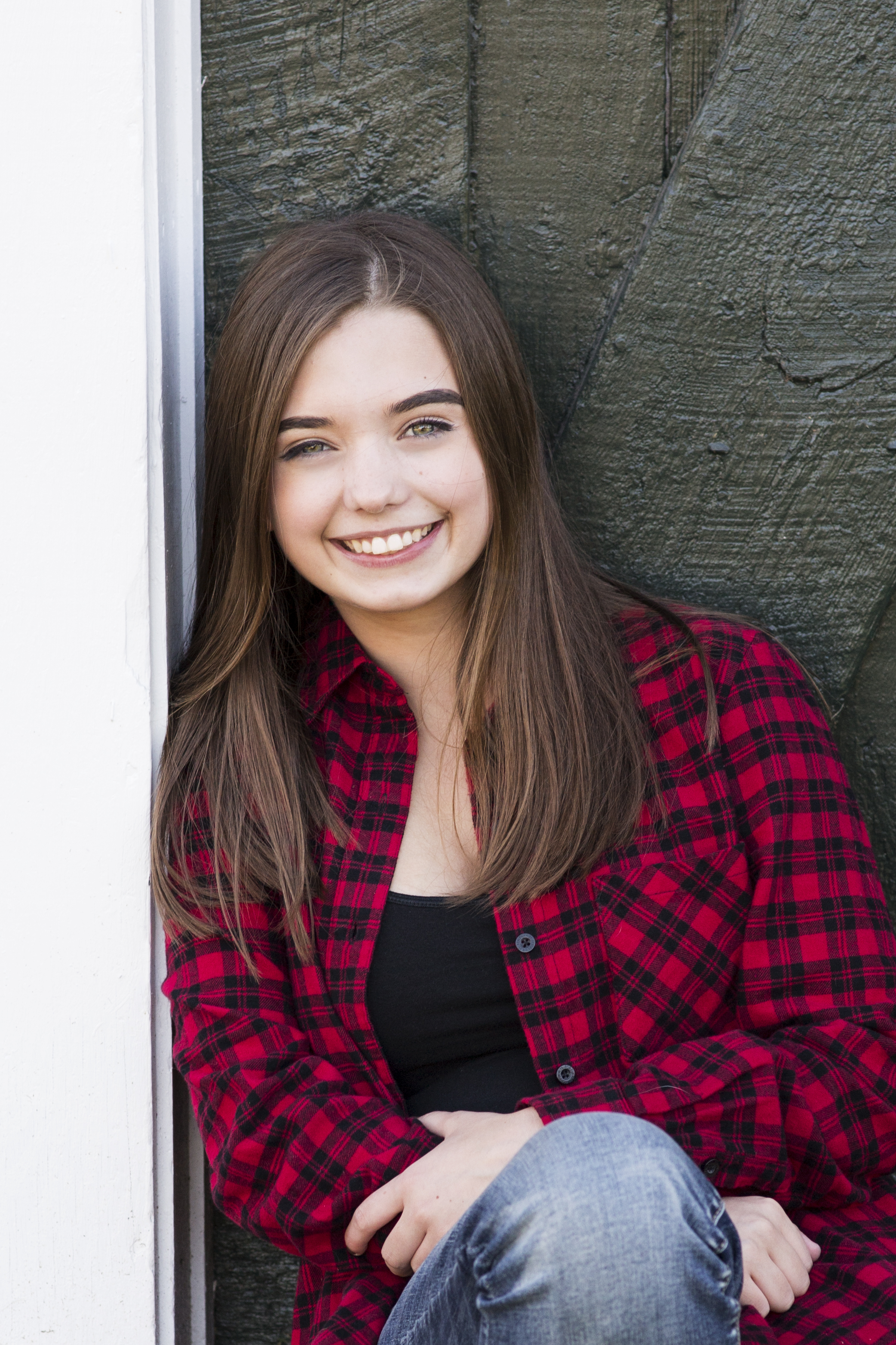 senior girl with brown hair in front of green wooden door