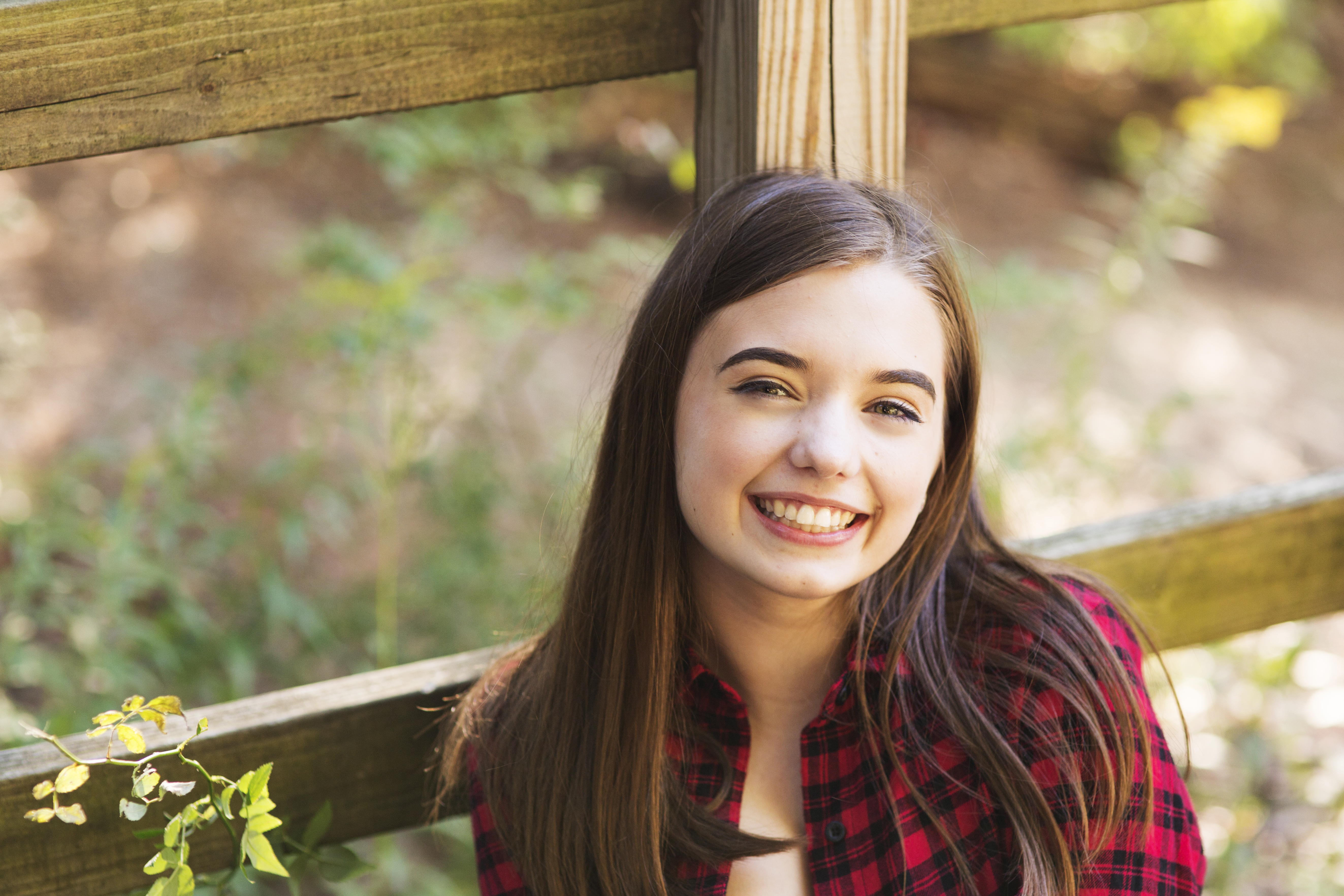 brown haired girl smiles at camera in senior portrait