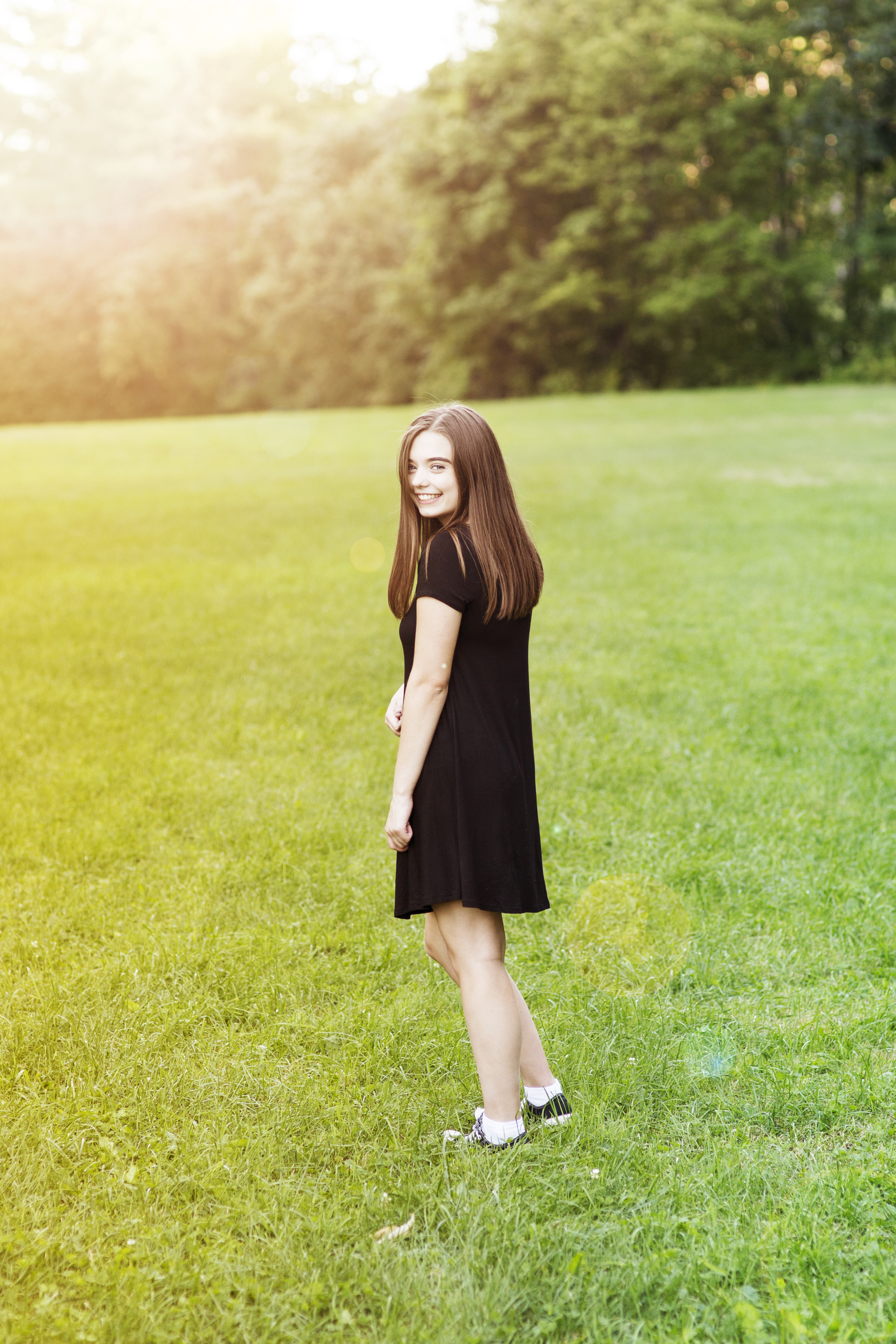 girl in black dress in grassy field senior golden hour portrait