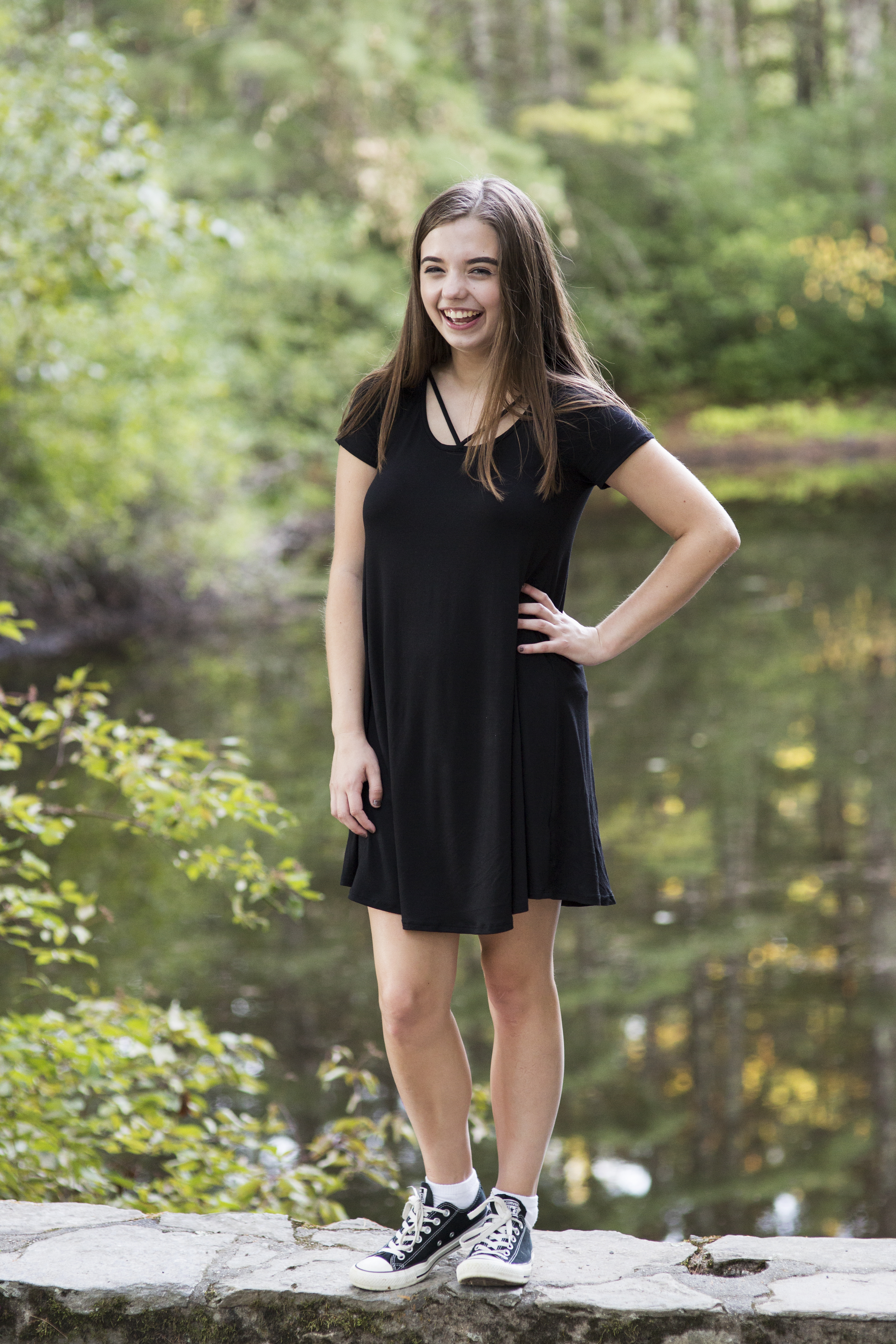 brown haired girl laughing senior portrait water in the woods