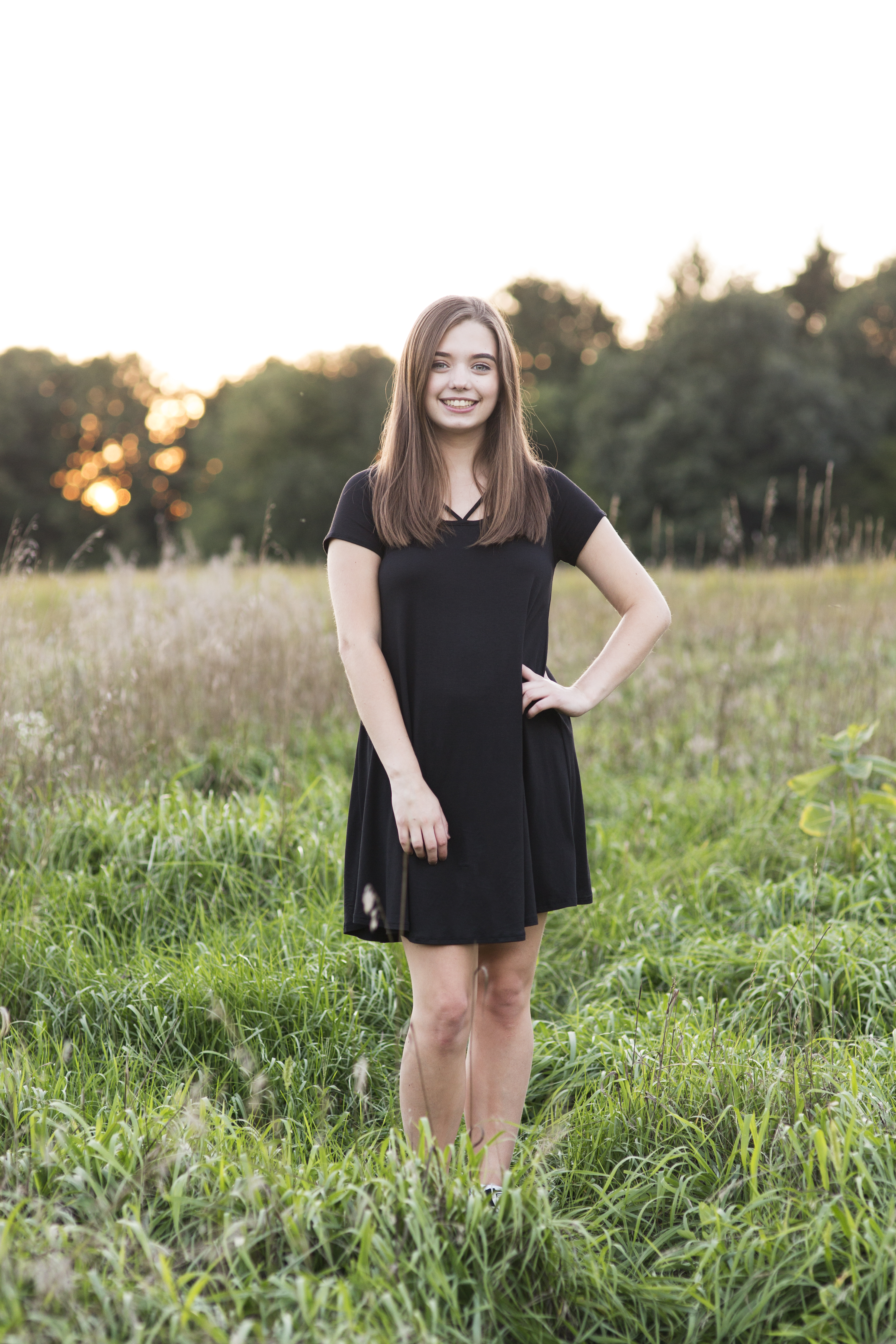 senior portraits of girl in field at golden hour