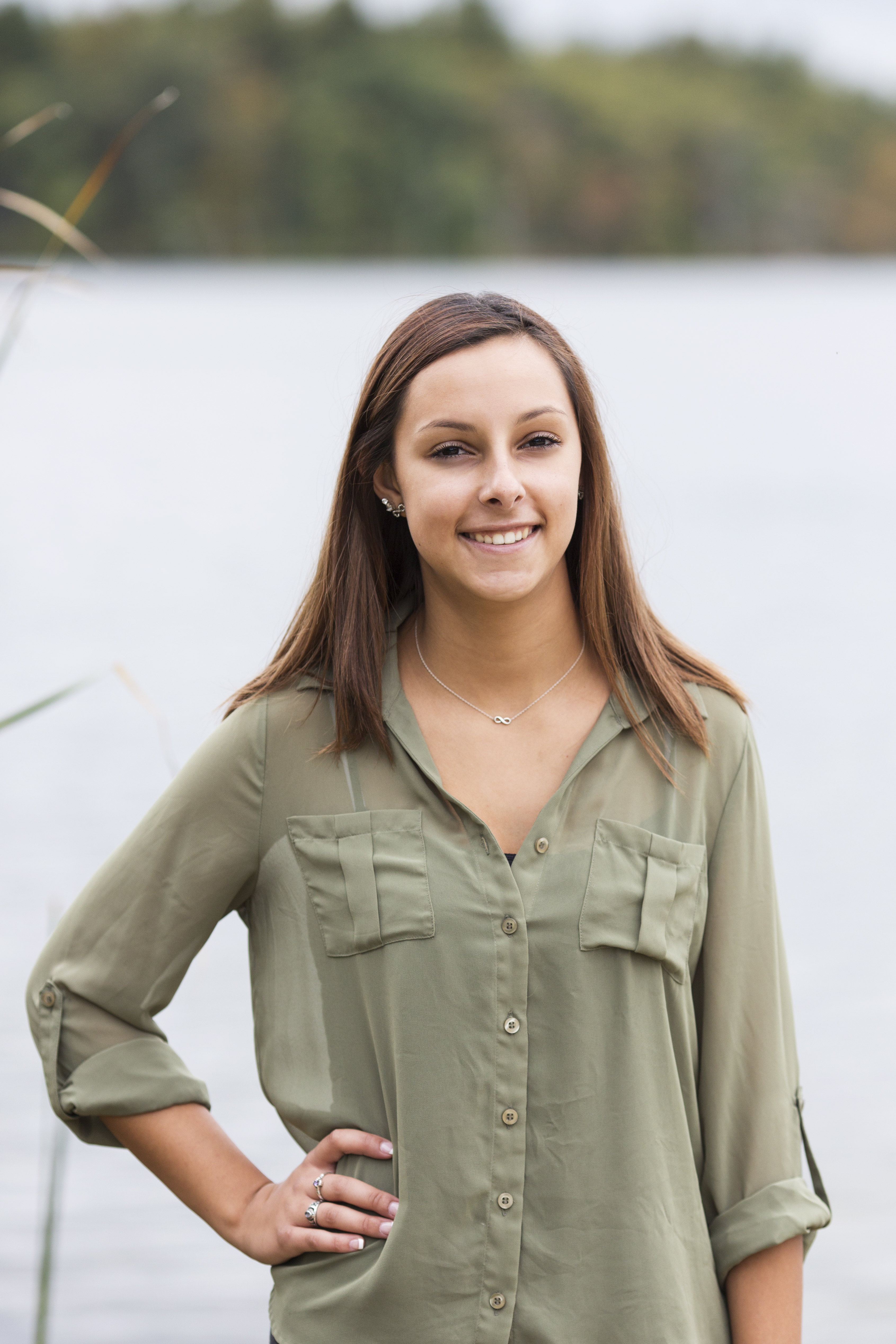 senior portrait outdoors by lake in fall girl in green shirt