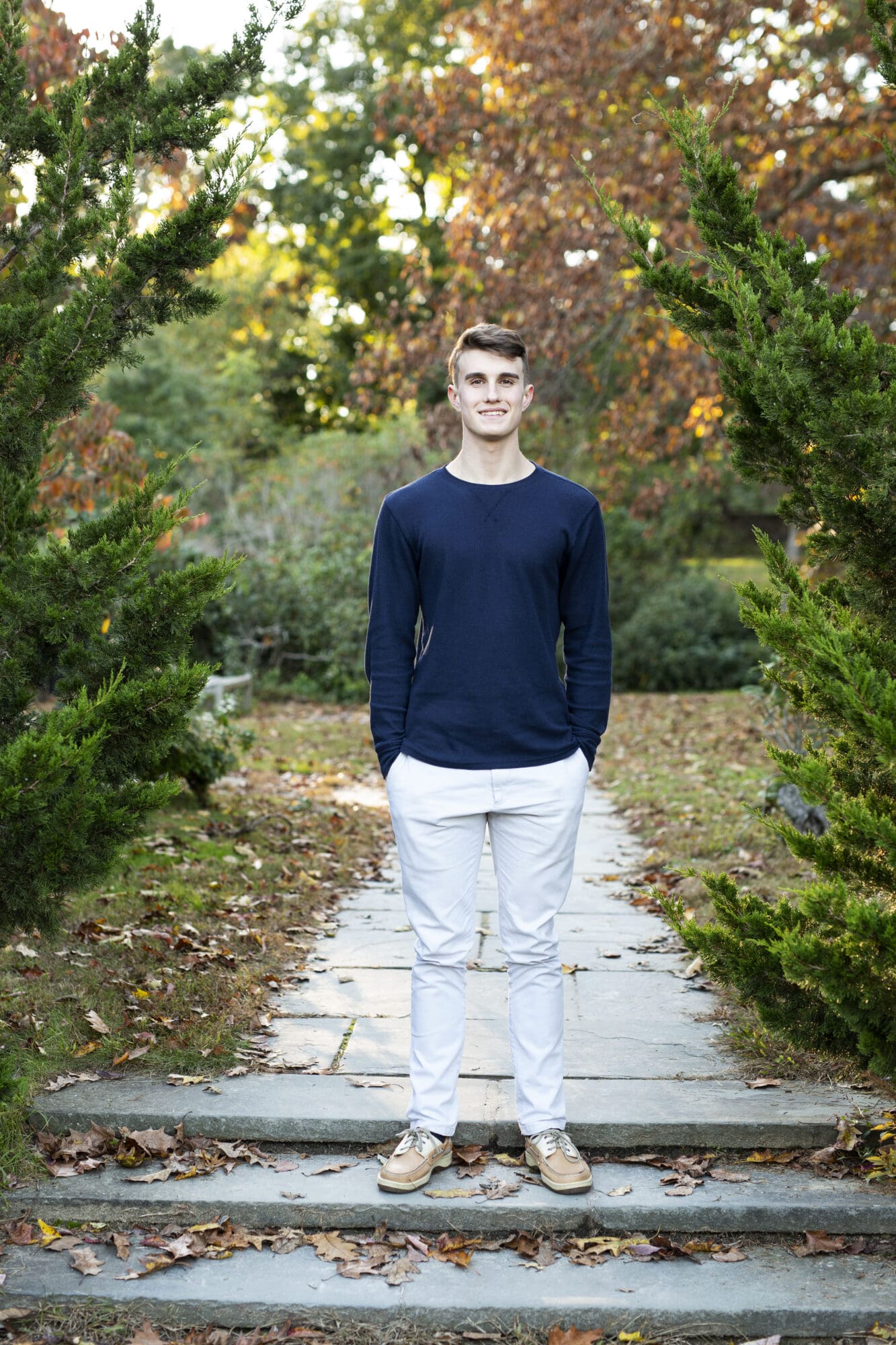 guy senior session standing on stone steps with fall leaves at golden hour