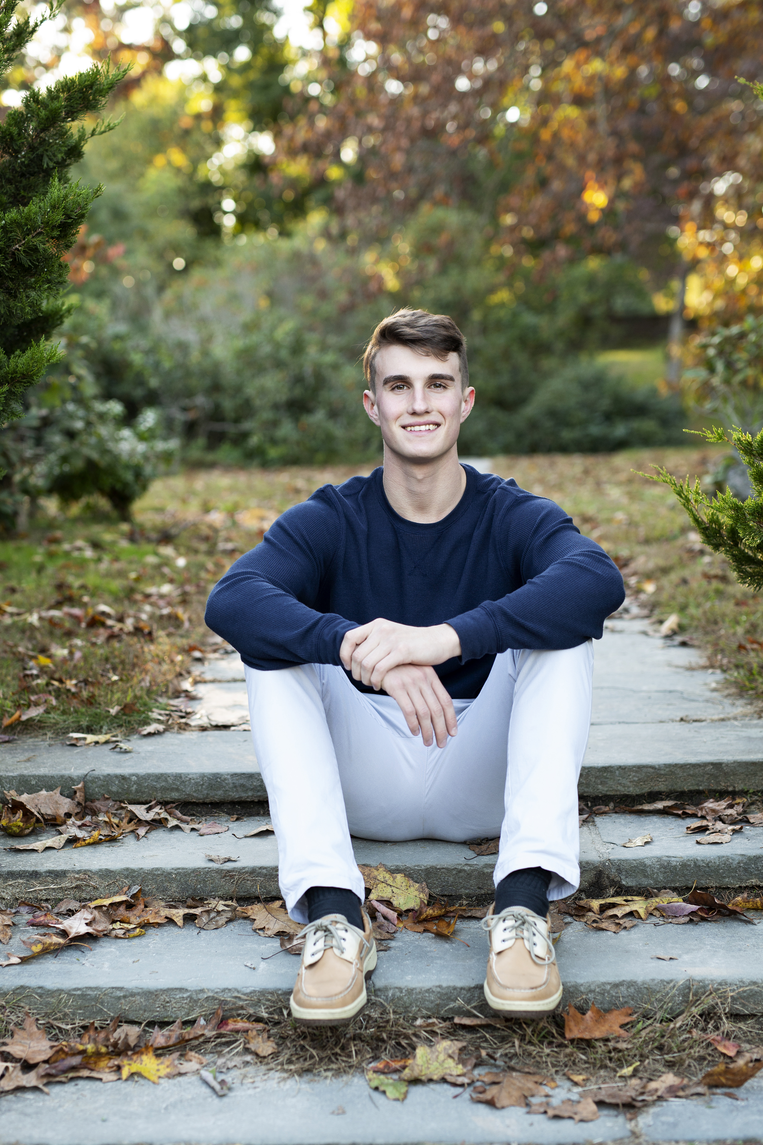 fall senior session with guy sitting on stone steps